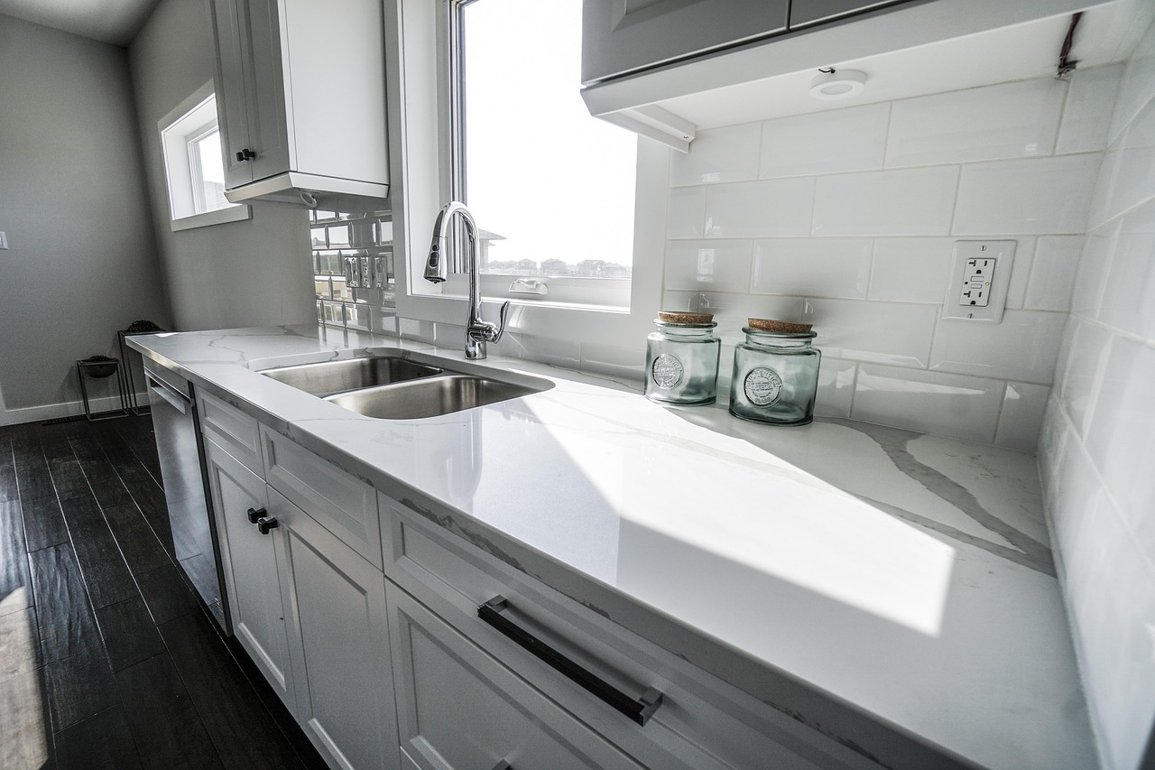Kitchen before treatment (desaturated clean still): scrubbed sink and chrome awaiting the after grade